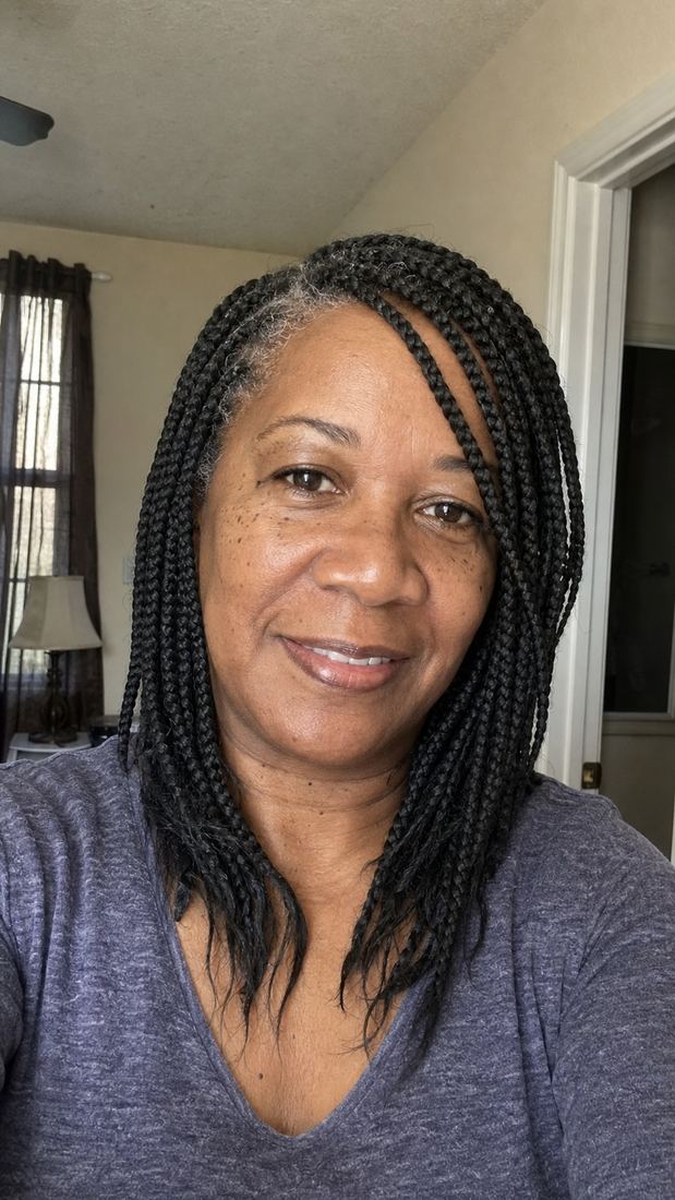 Black woman over 50 with medium box braids and a soft side part