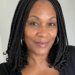 Black woman over 50 wearing shoulder-grazing medium knotless braids with a clean middle part