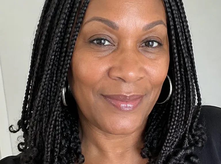 Black woman over 50 wearing shoulder-grazing medium knotless braids with a clean middle part