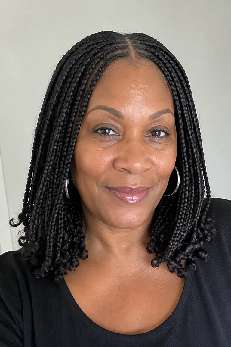 Black woman over 50 wearing shoulder-grazing medium knotless braids with a clean middle part