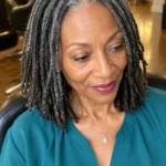 Black woman over 60 with shoulder-length salt-and-pepper locs and tapered ends.